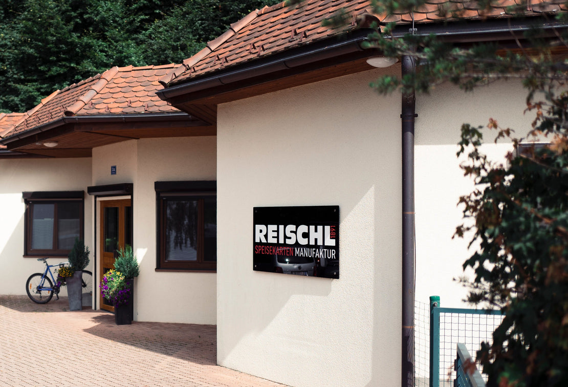 Außenansicht der Reischl Speisekarten Manufaktur in Österreich mit Firmengebäude und Eingangsbereich.