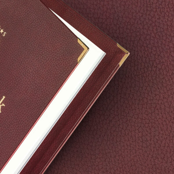 Detailaufnahme einer Speisekarte aus Designleder in der Farbe Burgund mit Metallecken in der Farbe Gold