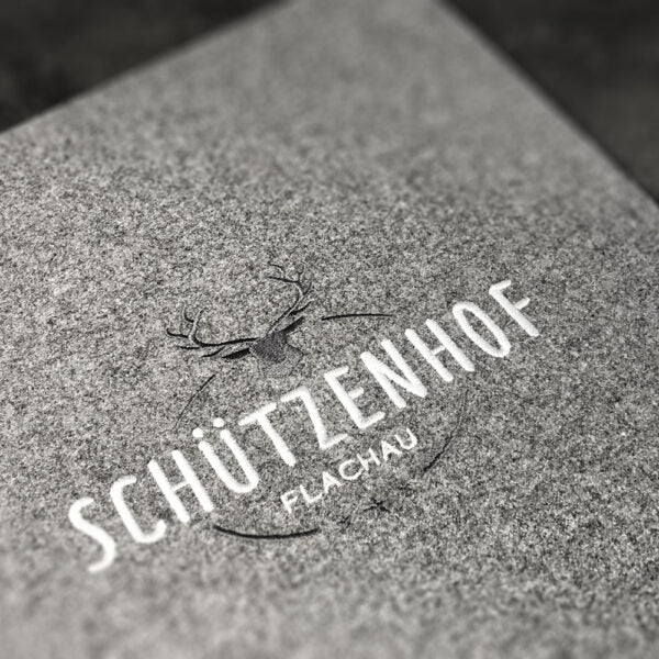Detailaufnahme einer Speisekarte aus Loden mit Stickerei auf der Vorderseite