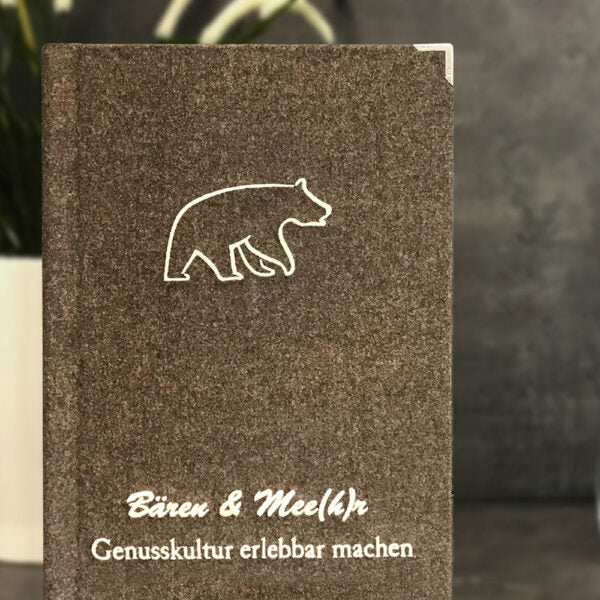 Detailaufnahme einer Speisekarte aus Loden mit Stickerei auf der Vorderseite