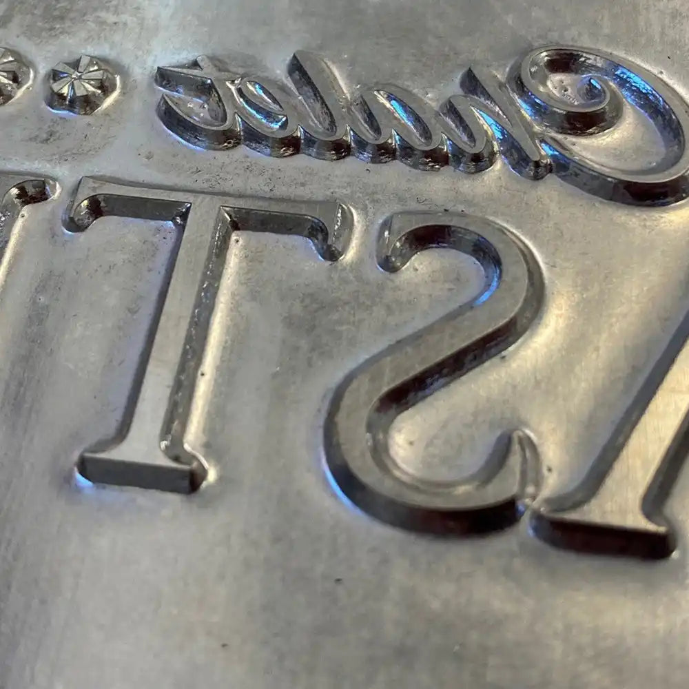 Detailaufnahme einer Prägung auf einer Speisekarte aus Aluminium